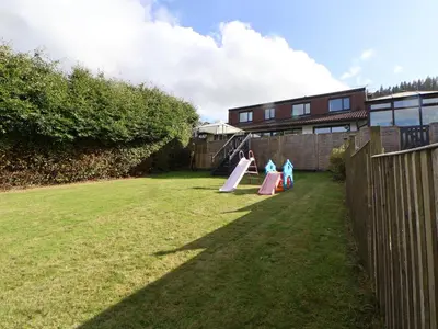 two children playing on a slide in a yard at Llangollen in Llangollen