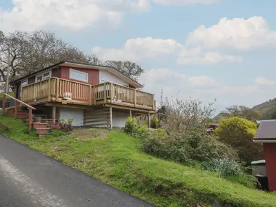 a house with a deck on the side of a road at Y Goedlan in Tywyn