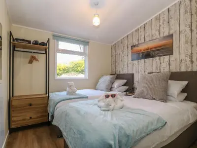 a bedroom with two beds and a window at Y Goedlan in Tywyn