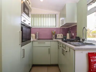 a kitchen with white cabinets and a sink at Y Goedlan in Tywyn