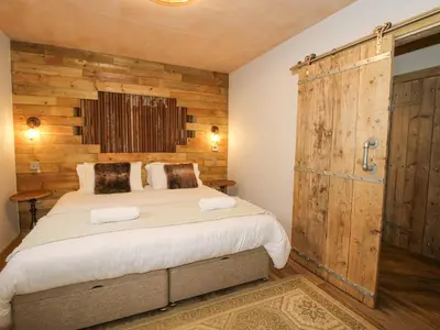 a bedroom with a large bed and a wooden wall at Bwncath in Welshpool