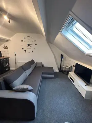 a living room with a couch and a clock on the wall at Rock Park Penthouse in Llandrindod Wells