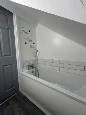 a bathroom with a bath tub and a sign on the wall at Rock Park Penthouse in Llandrindod Wells