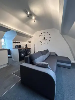 a living room with a couch and a clock on the wall at Rock Park Penthouse in Llandrindod Wells