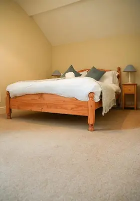 a bedroom with a wooden bed with white sheets and pillows at 3 Prospect Place, New Quay, sleeps 6, parking, sea views, dog friendly in New Quay