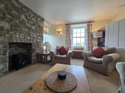 a living room with a fireplace and a stone wall at 3 Prospect Place, New Quay, sleeps 6, parking, sea views, dog friendly in New Quay