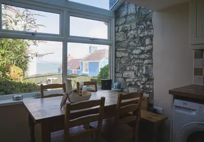 a dining room with a table and a large window at 3 Prospect Place, New Quay, sleeps 6, parking, sea views, dog friendly in New Quay
