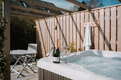 a bottle of champagne and two wine glasses on a tub at Hafan in Glasbury