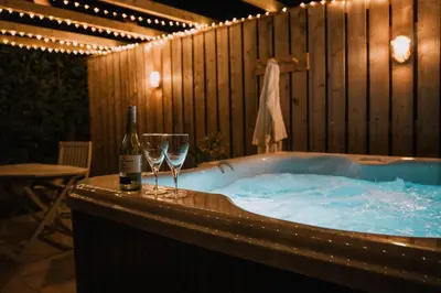a hot tub with a bottle of wine and two glasses at Hafan in Glasbury