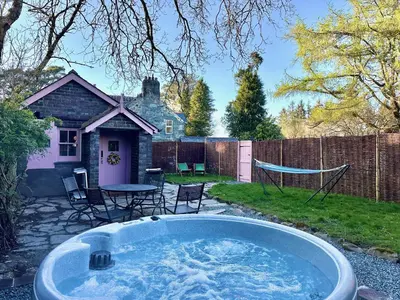 a hot tub in a yard with a table and chairs at Tiny Romantic Retreat with Hot Tub on a Country Estate near Cardigan Bay in Eryri Snowdonia in Llanbedr