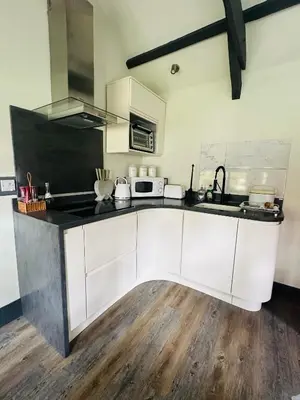 a kitchen with white cabinets and a black counter top at Tiny Romantic Retreat with Hot Tub on a Country Estate near Cardigan Bay in Eryri Snowdonia in Llanbedr