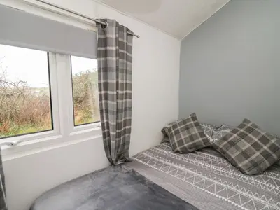 a small room with a bed and a window at Chalet 32 in Aberystwyth