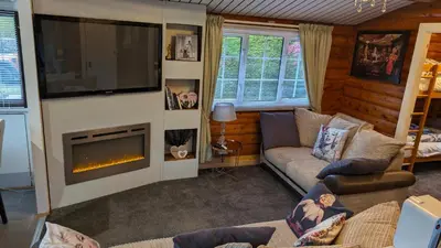 a living room with a couch and a fireplace at Snowdonia Log Cabin 2 in Trawsfynydd