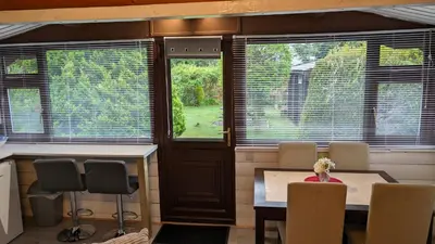 a room with a table and chairs and windows at Snowdonia Log Cabin 2 in Trawsfynydd