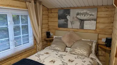 a bedroom with a bed and a window at Snowdonia Log Cabin 2 in Trawsfynydd