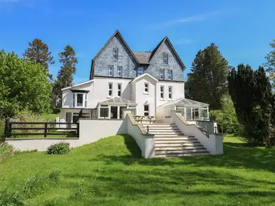 a large white house with a staircase in front of it at Serenity House, The Retreat in Llangammarch Wells