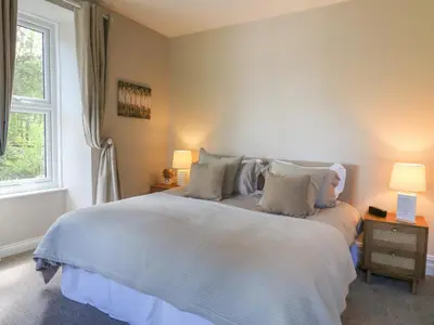 a bedroom with a white bed with two lamps and a window at Serenity House, The Retreat in Llangammarch Wells
