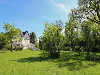 an outdoor swing set in a field in front of a house at Serenity House, The Retreat in Llangammarch Wells