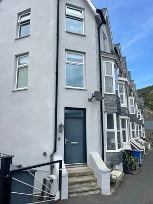 a white house with a blue door on a street at Harbour House in Barmouth