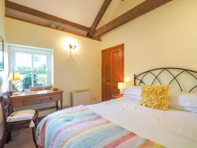 a bedroom with a bed and a desk and a window at Nyth y Wennol Aberaeron in Llanarth