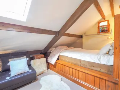 a attic bedroom with a bed and a couch at Nyth y Wennol Aberaeron in Llanarth