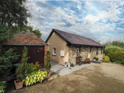 a stone house with a garage and a shed at Nyth y Wennol Aberaeron in Llanarth