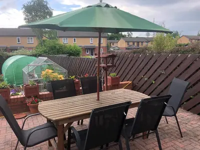 a wooden table with chairs and a green umbrella at Twyford Homestay B&B in Llandrindod Wells