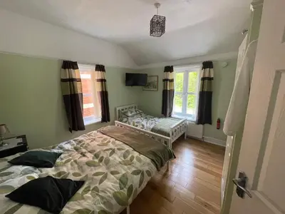 a bedroom with a bed and two windows at Twyford Homestay B&B in Llandrindod Wells