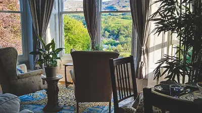 a living room with a large window and plants at Amazing Cader views Torrent en suite in Dolgellau