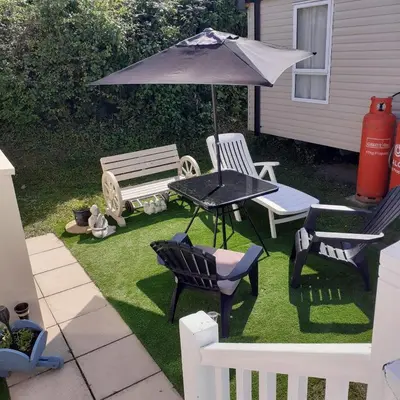 a patio with a table and chairs and an umbrella at 2 Bed Chalet - Sleeps 4 - Pets - Parking in New Quay