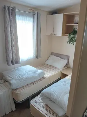 two beds in a room with a window at 2 Bed Chalet - Sleeps 4 - Pets - Parking in New Quay