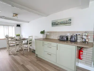 a kitchen with a counter and a table with chairs at 2 Penporth in Rhayader