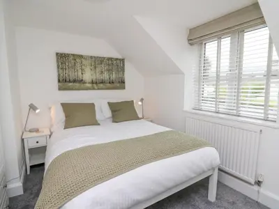 a white bedroom with a bed and a window at 2 Penporth in Rhayader