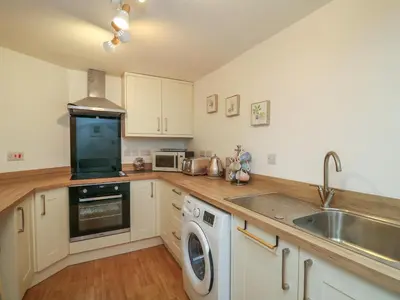 a kitchen with white cabinets and a sink and a washer at 1 Penporth in Rhayader