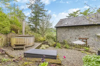 a garden with a wooden bench and a large tub at 3 Bed in Knighton oc-b29329 in Felindre