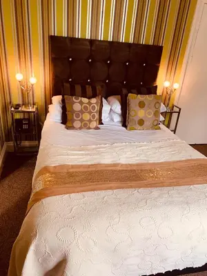 a bedroom with a large bed with white sheets and pillows at The Hotel Commodore in Llandrindod Wells