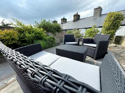 a patio with a table and wicker chairs at Ty Dyffryn in Blaenau-Ffestiniog
