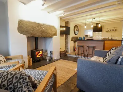 a living room with a fireplace and a kitchen at Ty Dyffryn in Blaenau-Ffestiniog
