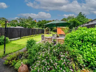 a garden with a table and a green umbrella at 3 Bedroom home within walking distance of town - Pass the Keys in Shrewsbury