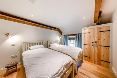 two beds in a bedroom with wooden floors and ceilings at 4 Bed in Derwenlas oc-c29244 in Machynlleth