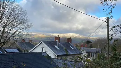 a group of roofs of houses with mountains in the background at Poets Cottage Eglwys Fach in Scyborycoed
