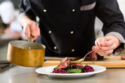 a chef preparing a plate of food on a table at Toad Hall in Church Stretton
