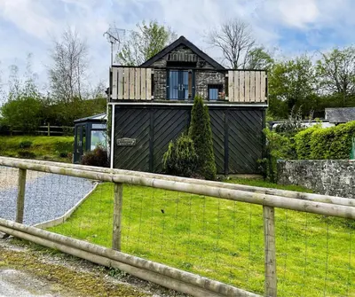 a black house with a fence in front of it at Horseshoe Cottage Aberaeron in Ciliau-Aeron
