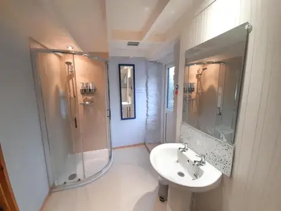 a white bathroom with a shower and a sink at Horseshoe Cottage Aberaeron in Ciliau-Aeron