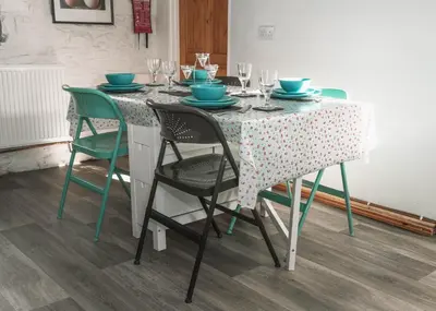 a table with chairs and plates and wine glasses at Horseshoe Cottage Aberaeron in Ciliau-Aeron