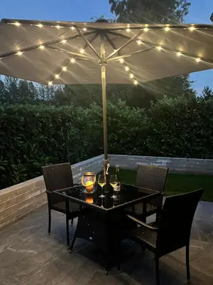 a table and chairs under an umbrella on a patio at Lilac Cottage in Stoke Prior