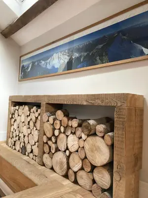 a fireplace filled with logs in a room at Ty Bach Coch in Scethrog