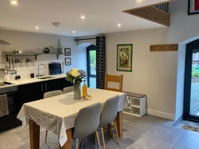a kitchen and dining room with a table and chairs at Ty Bach Coch in Scethrog