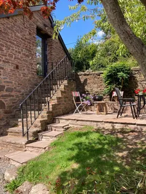 a brick house with stairs and a table and chairs at Ty Bach Coch in Scethrog