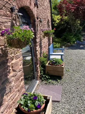 a garden with a blue chair and some flowers at Ty Bach Coch in Scethrog